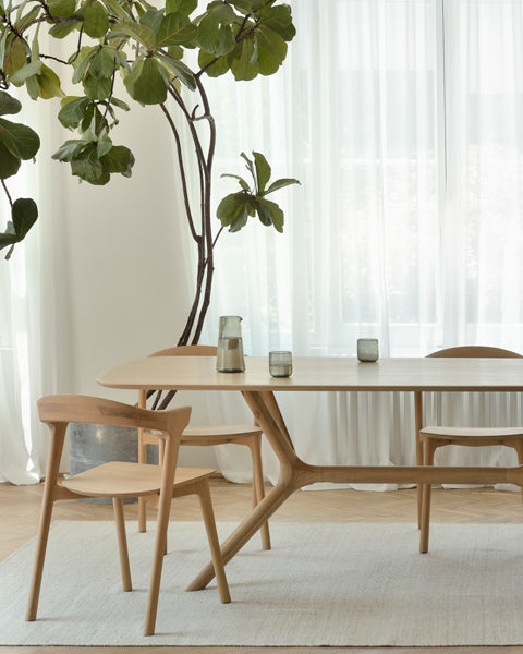 X Dining Table by Ethnicraft, showing closeup view of oak x dining table with chairs in live shot.