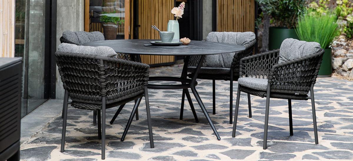 Ocean Stackable Dining Chair by Cane-Line, showing ocean stackable dining chairs with table in live shot.