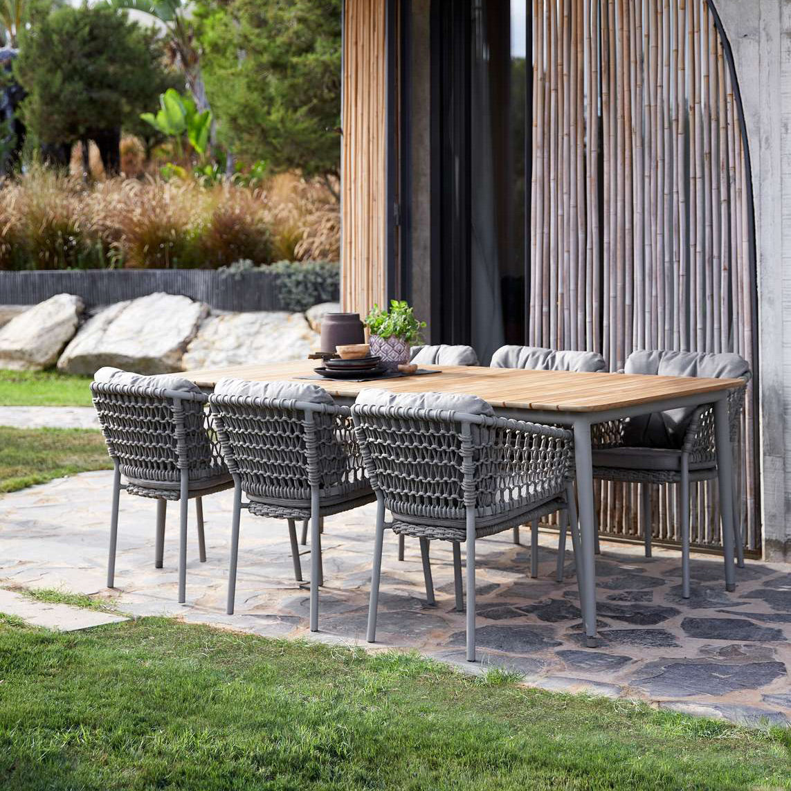 Ocean Stackable Dining Chair by Cane-Line, showing ocean stackable dining chairs with table in live shot.