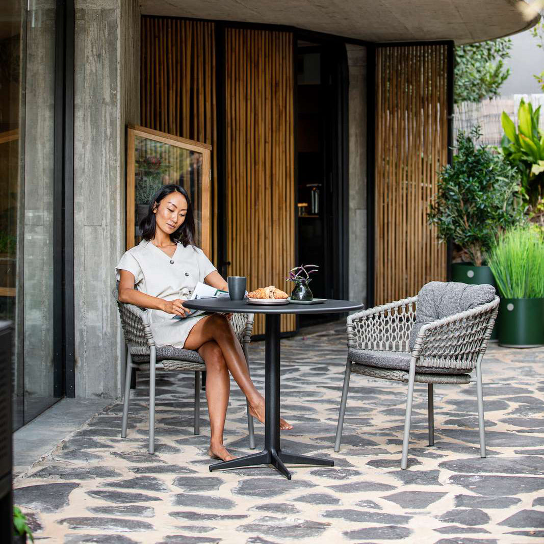 Ocean Stackable Dining Chair by Cane-Line, showing ocean stackable dining chairs with table in live shot.