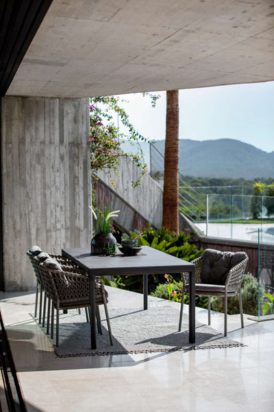 Ocean Stackable Dining Chair by Cane-Line, showing ocean stackable dining chairs with table in live shot.