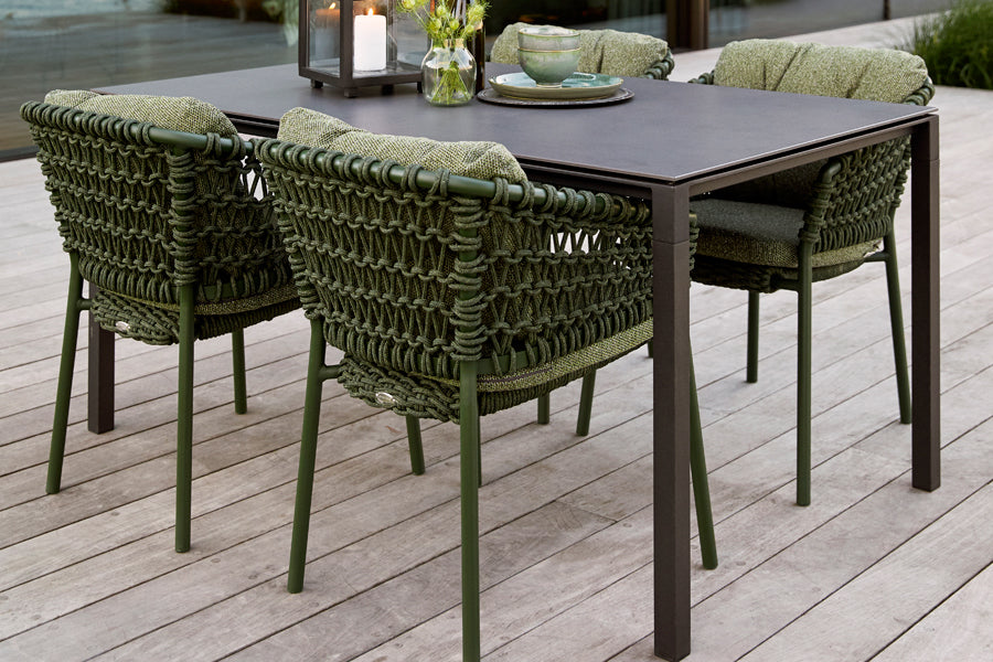 Ocean Stackable Dining Chair by Cane-Line, showing ocean stackable dining chairs with table in live shot.