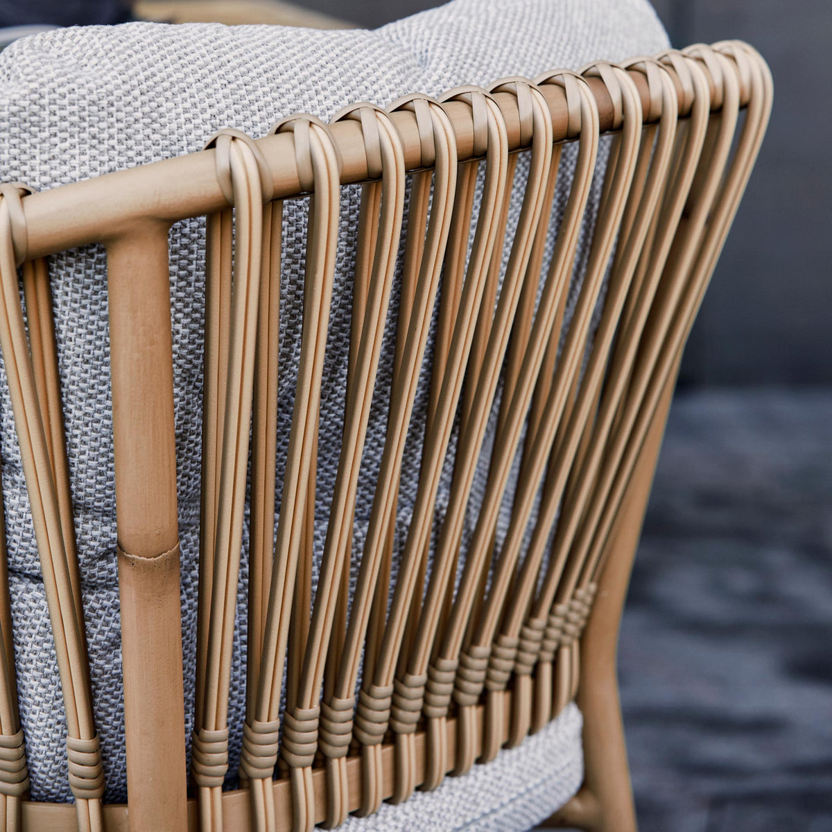 Ocean Stackable Natural/Aluminum Dining Chair by Cane-Line, showing closeup view of ocean stackable natural/aluminum dining chair in live shot.
