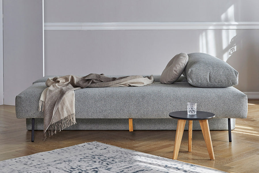 Osvald Sofa Bed by Innovation, showing osvald sofa bed as bed size with table in live shot.