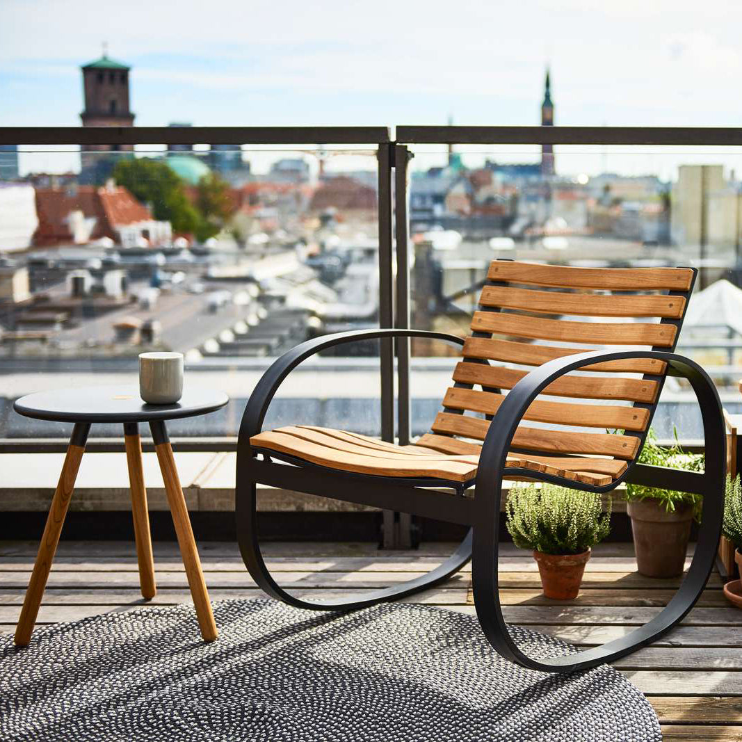 Parc Rocking Chair by Cane-Line, showing parc rocking chair with table in live shot.