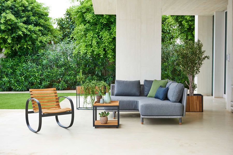 Parc Rocking Chair by Cane-Line, showing parc rocking chair with table & sectional in live shot.