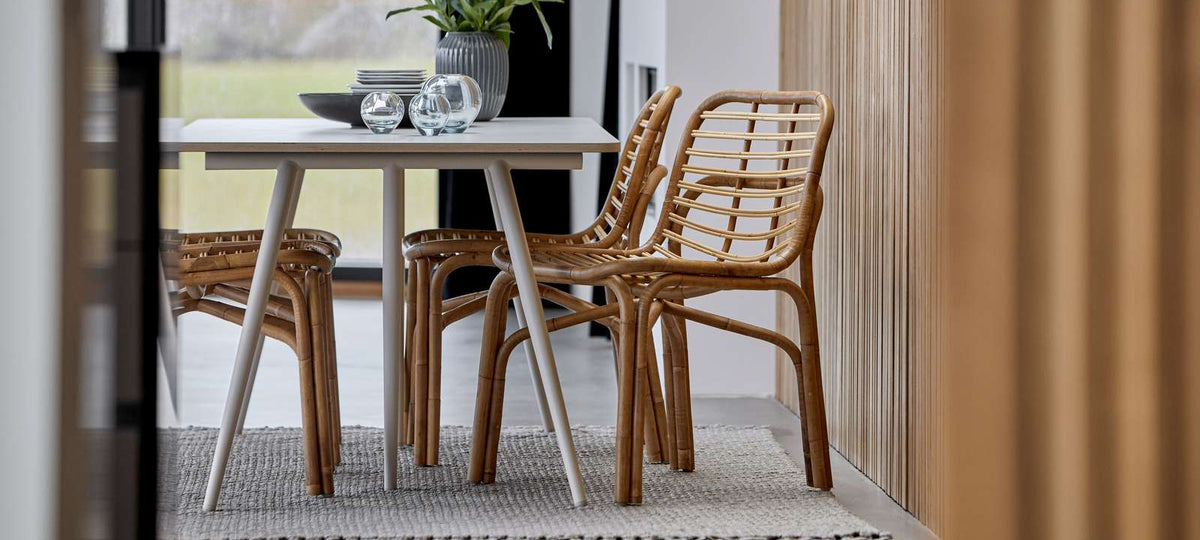 Peak Rattan Dining Chair by Cane-Line, showing peak rattan dining chairs with table in live shot.