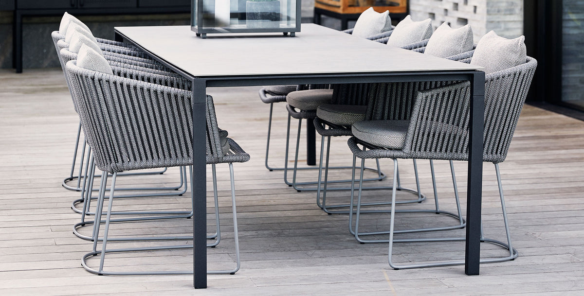 Pure 110.3" Aluminum Rectangular Dining Table by Cane-Line, showing pure 110.3" aluminum rectangular dining table with dining chairs in live shot.