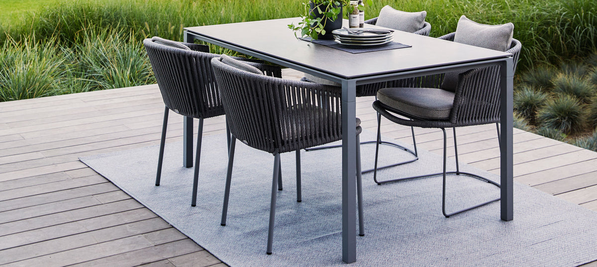 Pure 59.1" Aluminum Rectangular Dining Table by Cane-Line, showing pure 59.1" aluminum rectangular dining table with dining chairs in live shot.