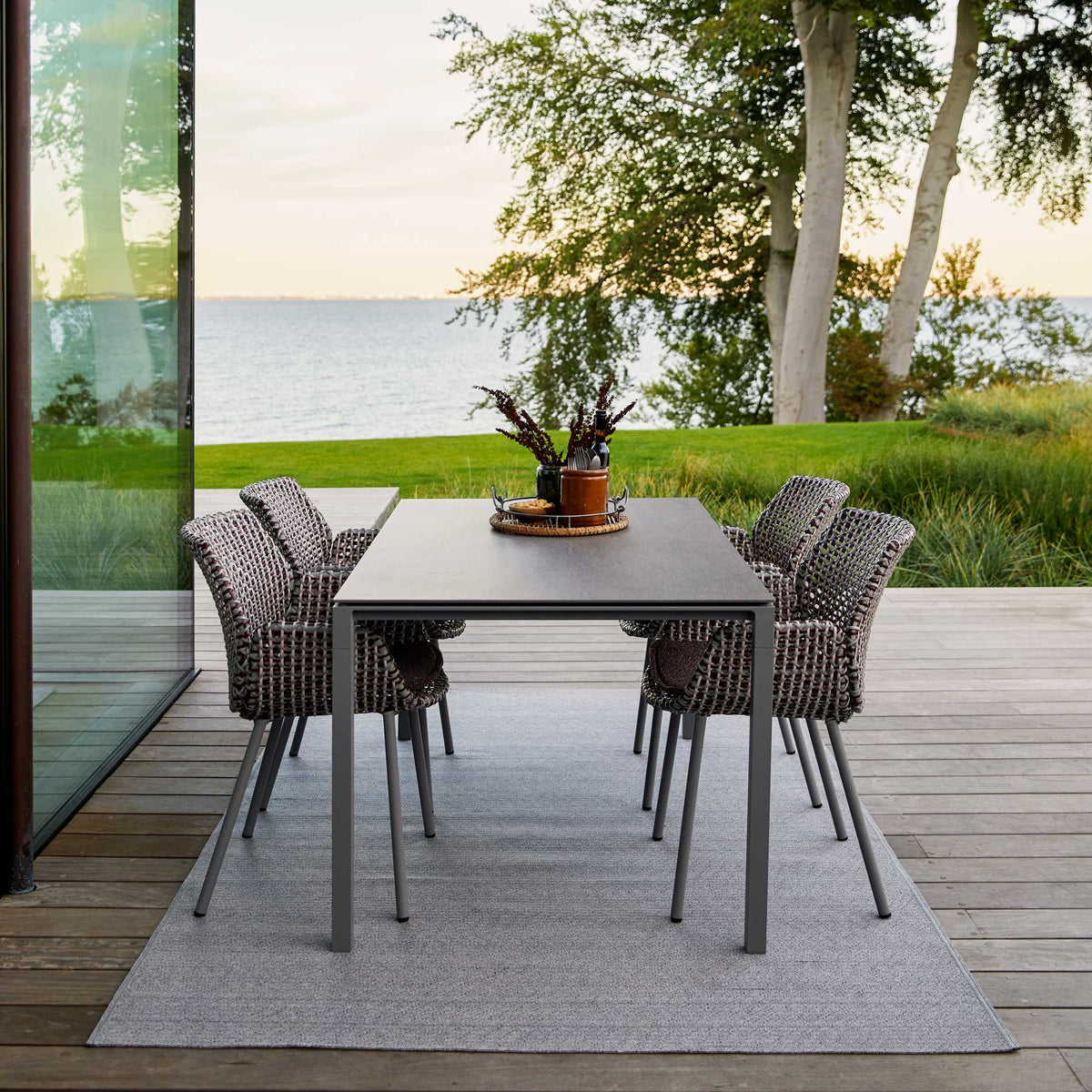 Pure 59.1" Aluminum Rectangular Dining Table by Cane-Line, showing pure 59.1" aluminum rectangular dining table with dining chairs in live shot.