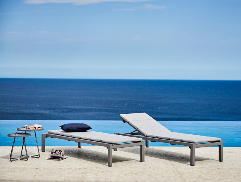 Relax Stackable Sunbed by Cane-Line, showing relax stackable sunbeds with tables in live shot.