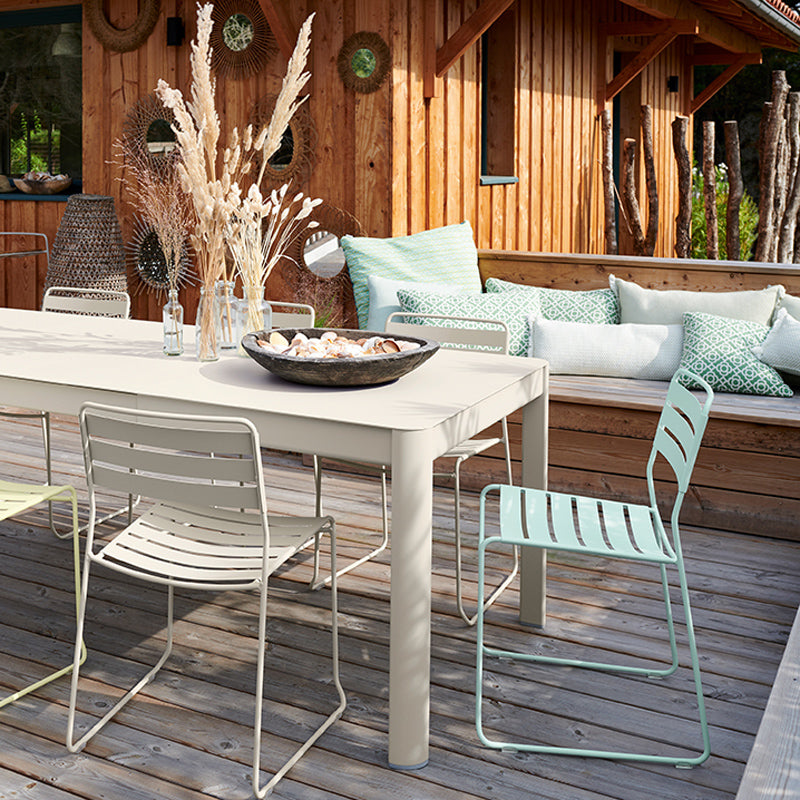 Ribambelle Table with 2 Extension by Fermob, showing closeup view of ribambelle table with 2 extension with chairs in live shot.