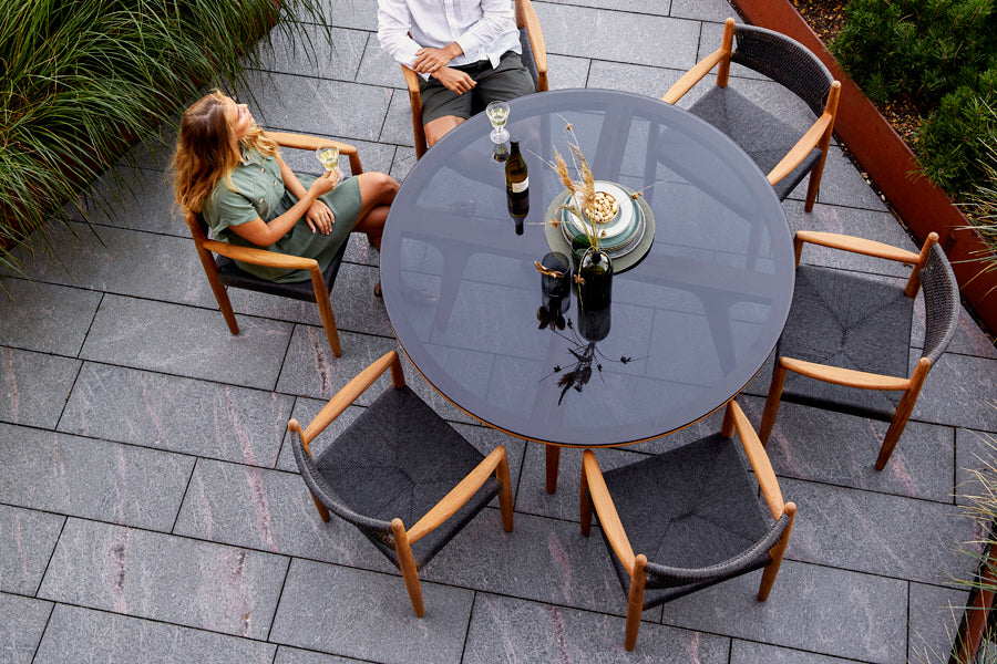 Royal Outdoor Dining Armchair by Cane-Line, showing royal outdoor dining armchairs with table in live shot.