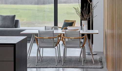 Sidd Stackable Dining Armchair by Cane-Line, showing sidd stackable dining armchairs with table in live shot.