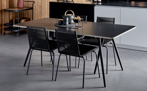 Sidd Stackable Dining Chair by Cane-Line, showing sidd stackable dining chairs with table in live shot.
