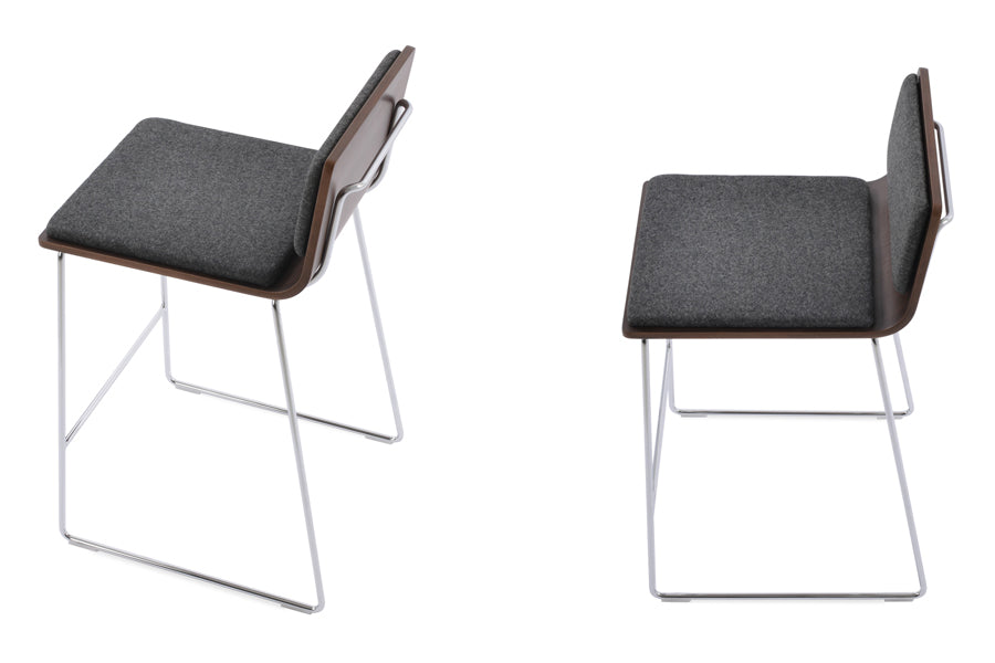 Corona Handle Back Wire Counter Stool by SohoConcept, showing angle view of two stools in camira blazer dark grey wool pads, american walnut plywood seat with chrome wire base.