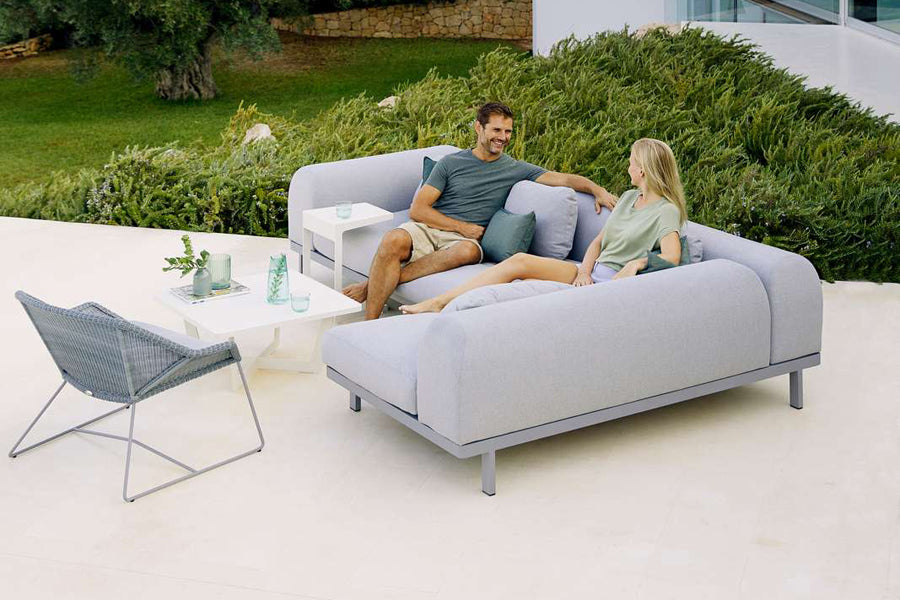 Space 2-Seater Module Sofa by Cane-Line, showing space 2-seater module sofas with table in live shot.