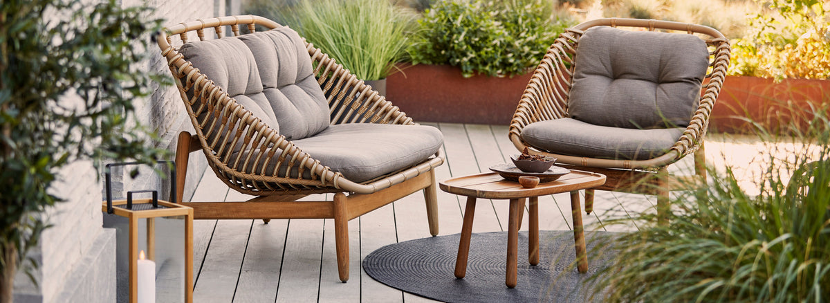 Strington Outdoor Teak 2-Seater Sofa by Cane-Line, showing strington outdoor teak 2-seater sofa with chair & table in live shot.