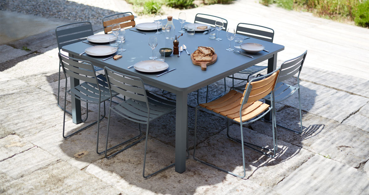 Surprising Teak Chair by Fermob, showing angle view of chair with table in the live shot.