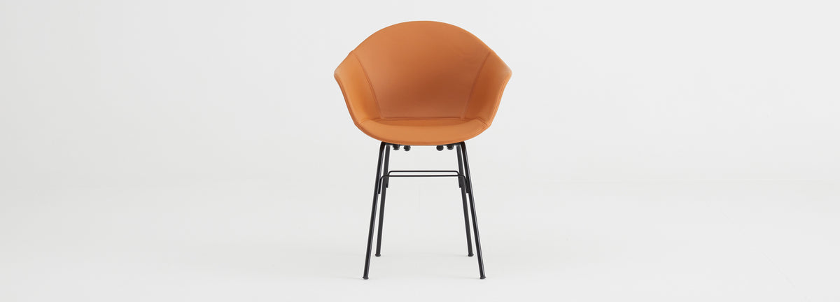 TA Upholstered Armchair by Toou, showing front view of ta upholstered armchair er in black base/cognac pu shell seat.