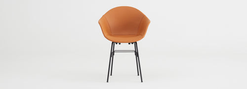 TA Upholstered Armchair by Toou, showing front view of ta upholstered armchair er in black base/cognac pu shell seat.