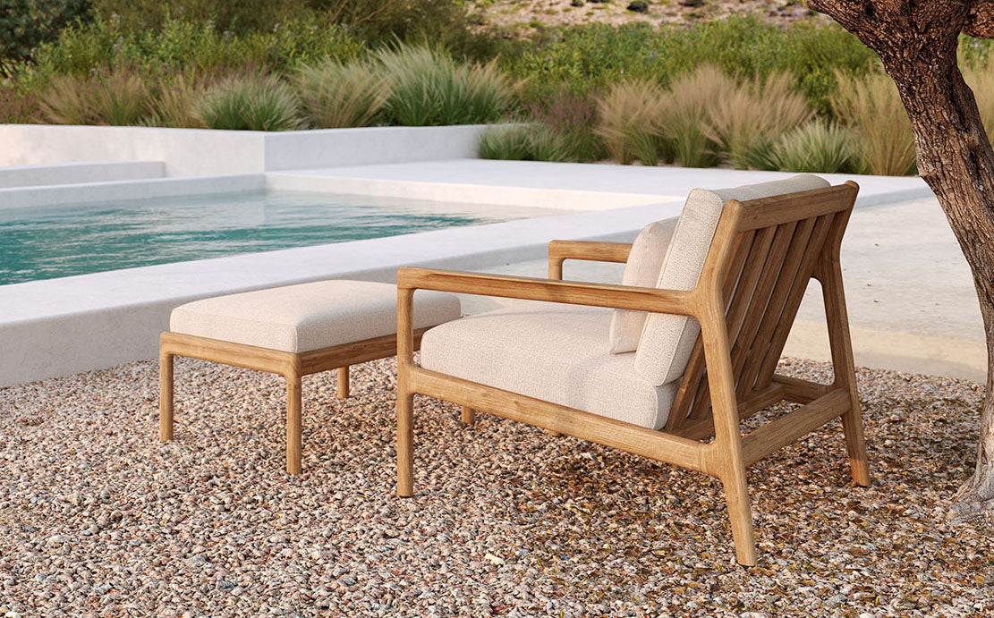 Jack Outdoor Footstool by Ethnicraft, showing front view of footstool with chair in the live shot.