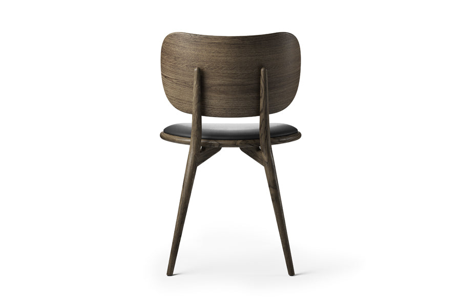 The Dining Chair by Mater, showing back view of the dining chair in sirka grey stained oak/black leather seat.