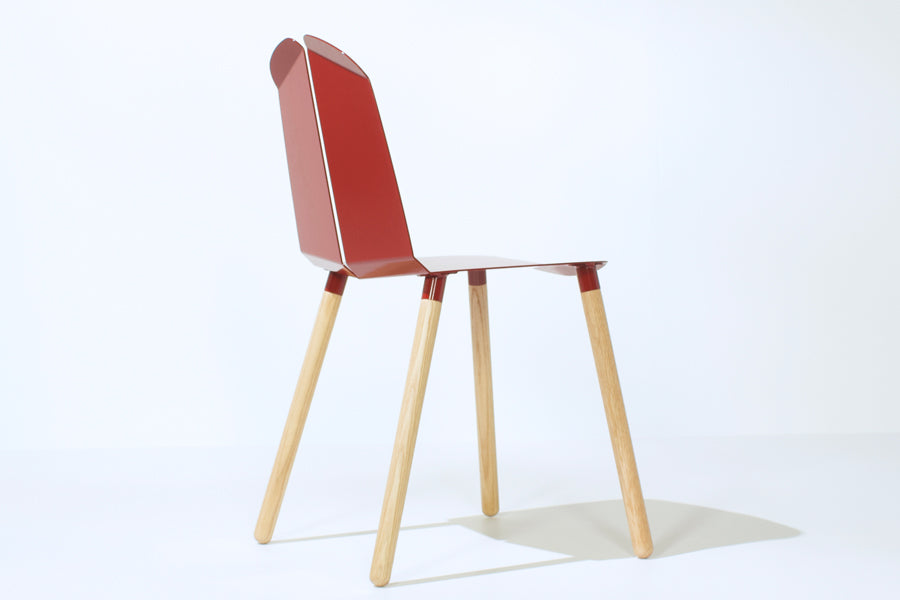 Noa Chair by Tronk Design, showing back angle view of noa chair in blood red powder coated steel seat/natural oak legs.