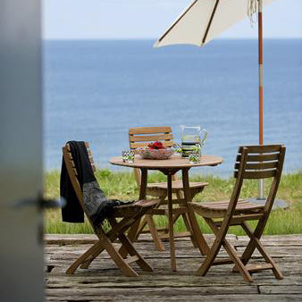 Vendia Chair by Skagerak, showing vendia chairs with table & umbrella in live shot.