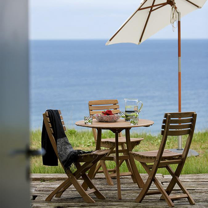 Vendia Table by Skagerak, showing vendia table with chairs & umbrella in live shot.