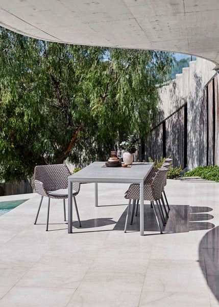 Vibe Outdoor Dining Chair by Cane-Line, showing vibe outdoor dining chairs with table in live shot.