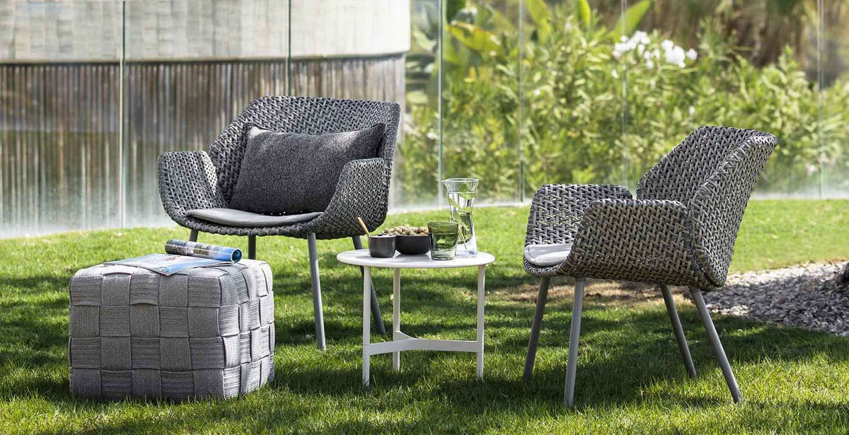 Vibe Outdoor Lounge Chair by Cane-Line, showing vibe outdoor lounge chairs with table & stool in live shot.