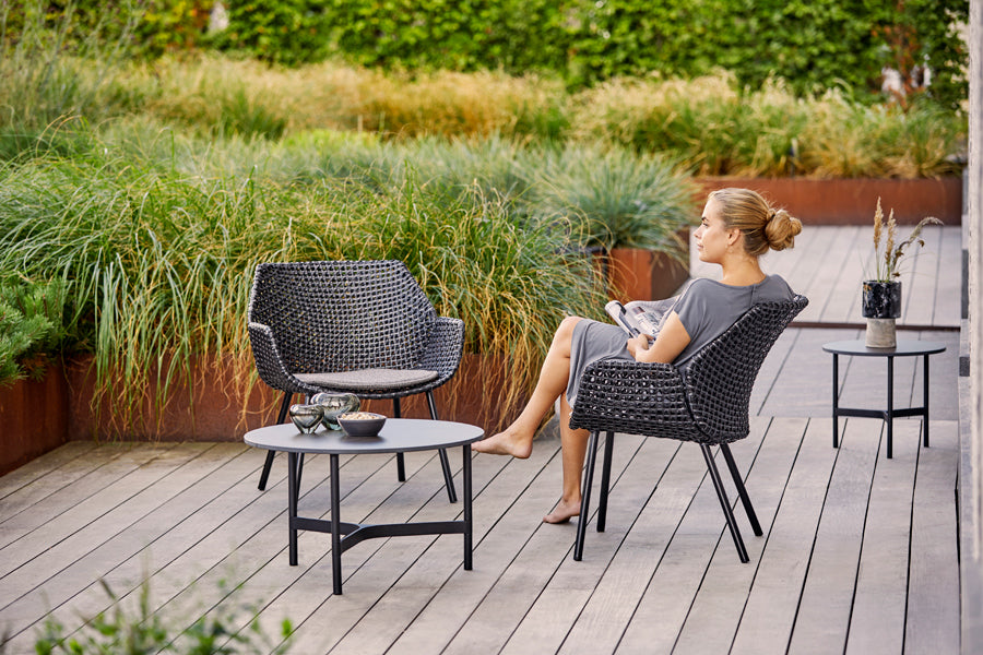 Vibe Outdoor Lounge Chair by Cane-Line, showing vibe outdoor lounge chairs with tables in live shot.