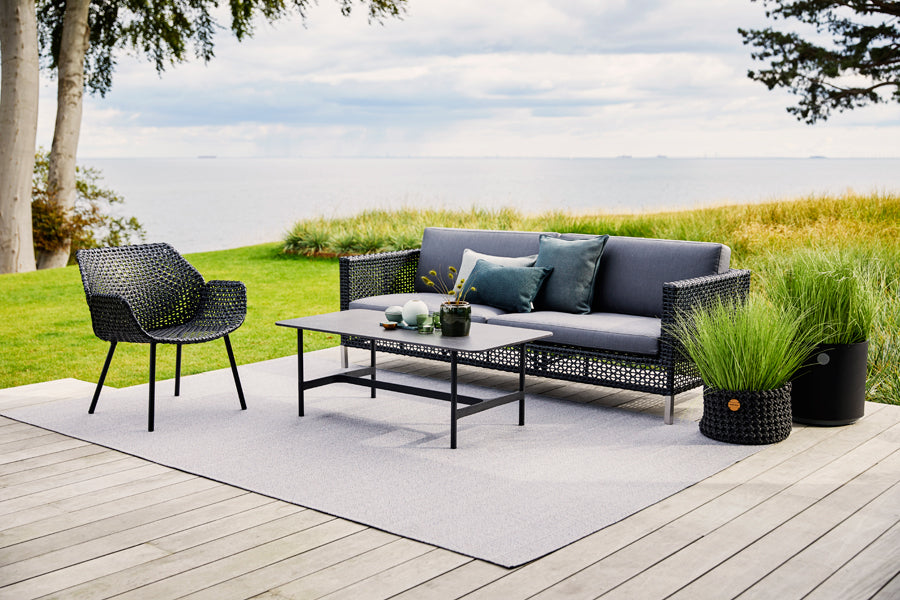 Vibe Outdoor Lounge Chair by Cane-Line, showing vibe outdoor lounge chair with table & sofa in live shot.