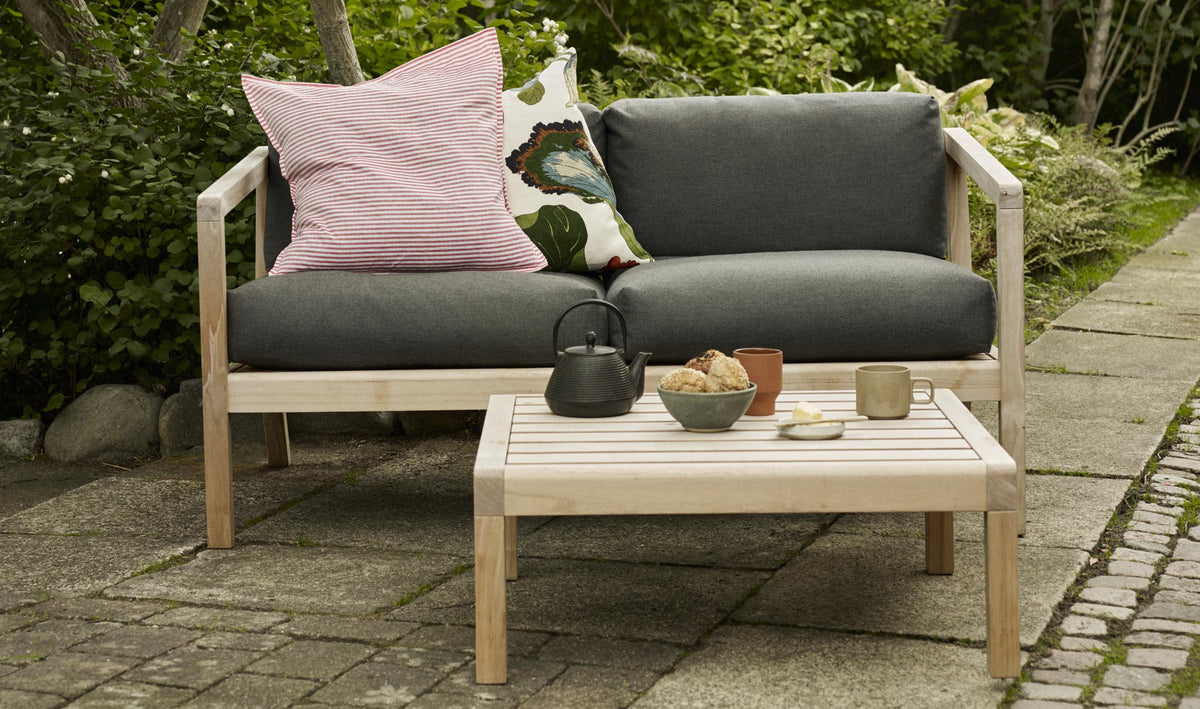 Virkelyst 2-Seater Sofa by Skagerak, showing virkelyst sofa with side table in live shot.