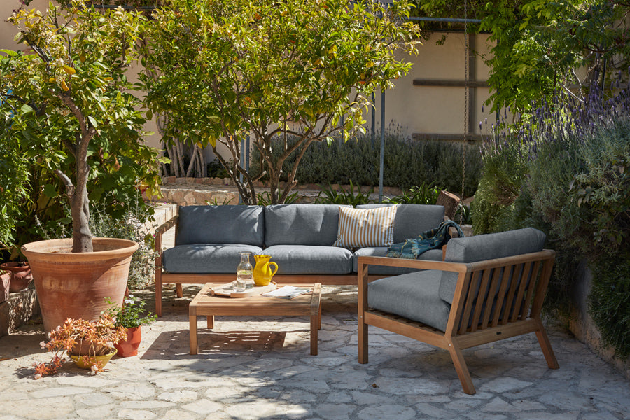 Virkelyst Chair by Skagerak, showing virkelyst chair with sofa & side table in live shot.