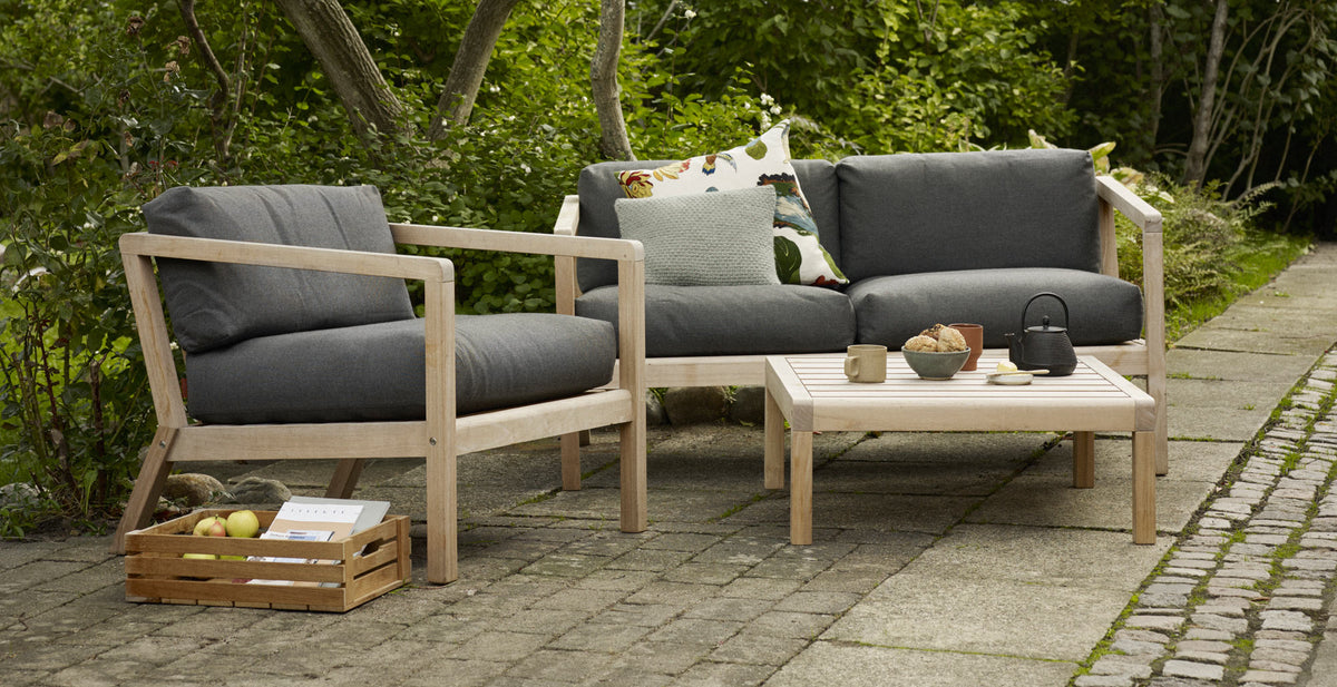 Virkelyst Chair by Skagerak, showing virkelyst chair with sofa & side table in live shot.