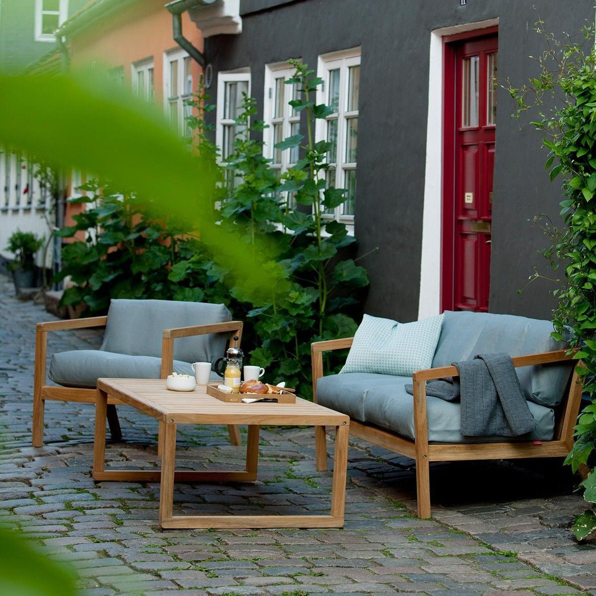 Virkelyst Coffee Table by Skagerak, showing virkelyst coffee table with sofa & chair in live shot.