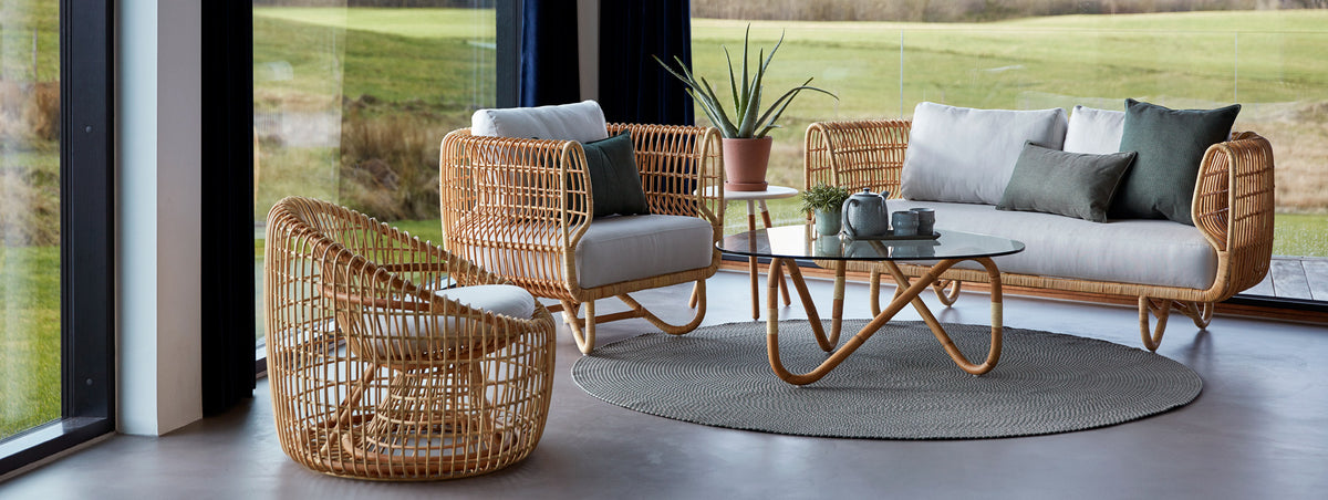 Wave Indoor Large Glass Coffee Table by Cane-Line, showing wave indoor large glass coffee table with sofa & chairs in live shot.