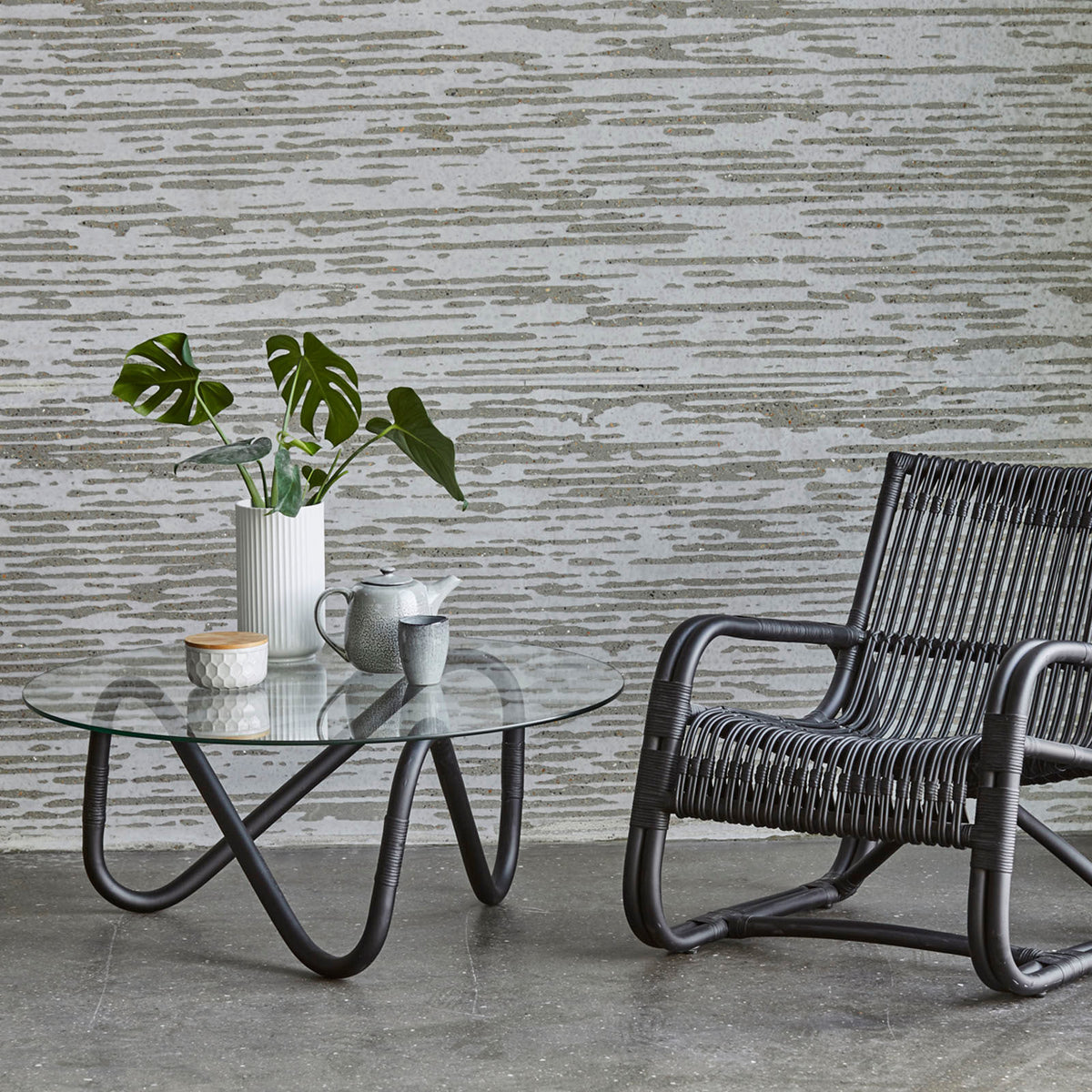 Wave Indoor Large Glass Coffee Table by Cane-Line, showing wave indoor large glass coffee table with chair in live shot.