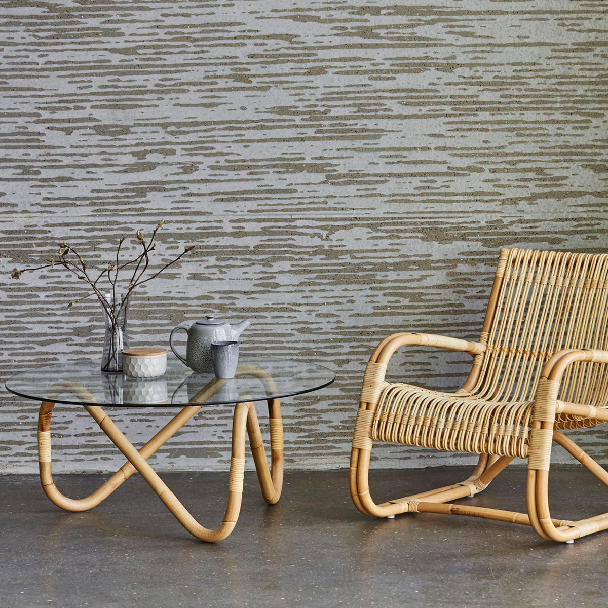 Wave Indoor Large Glass Coffee Table by Cane-Line, showing wave indoor large glass coffee table with chair in live shot.