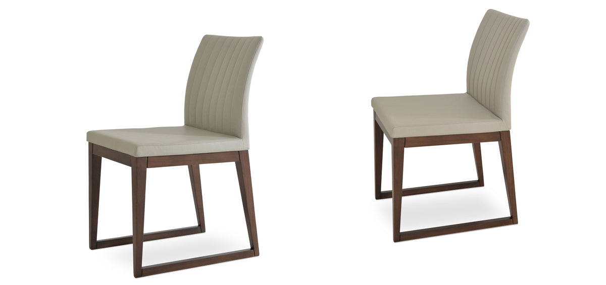 Zeyno Sled Wood Chair by sohoConcept, showing two chairs in light grey leatherette with walnut finish base.